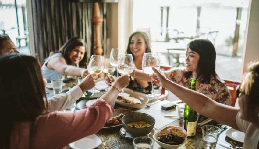 A group of women toasting wine glasses at a dinner table.