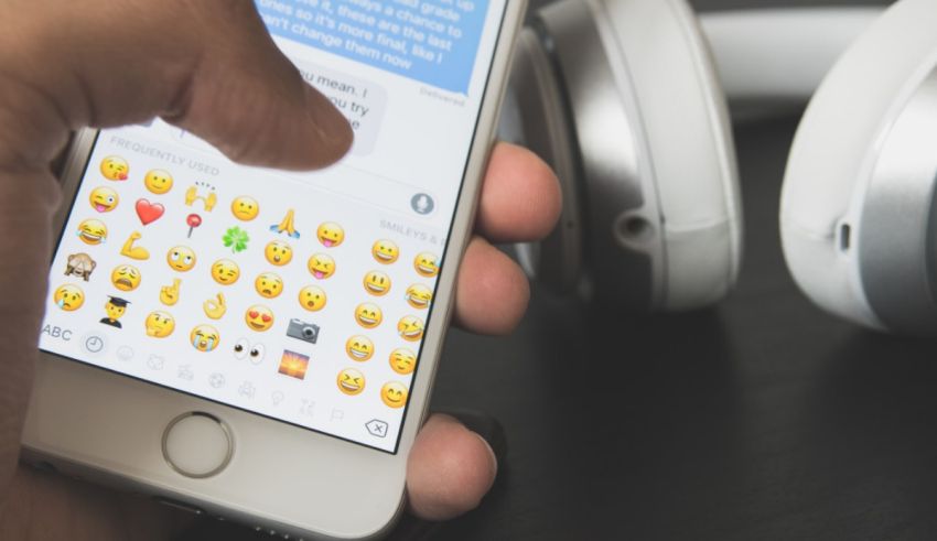 A person holding an iphone with emojis on it.