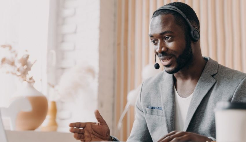 A black man wearing a headset while working on a laptop.