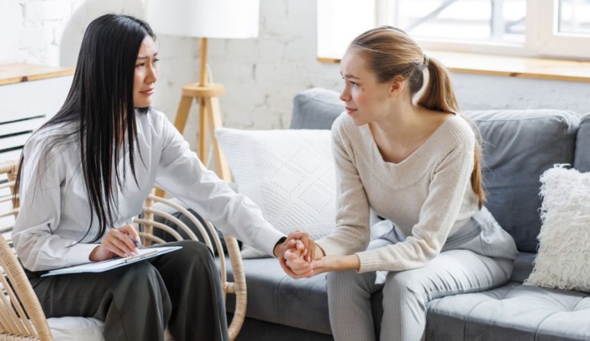 Two women sitting on a couch talking to a therapist.