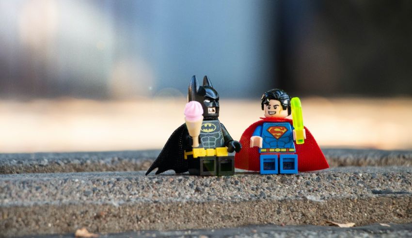 Lego batman and superman standing next to each other.