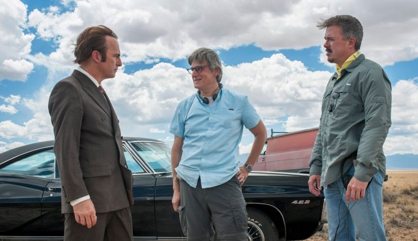 Three men standing next to a car in the desert.