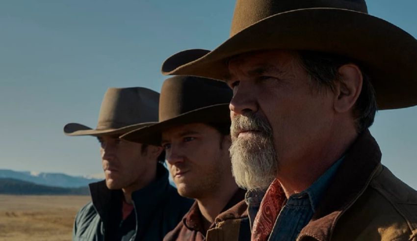 Three men in cowboy hats standing in a field.