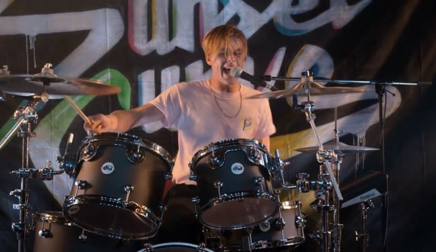 A young man playing drums on stage.