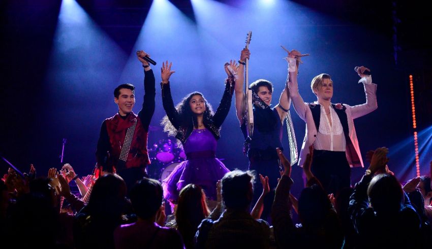 A group of people on stage with their hands up.