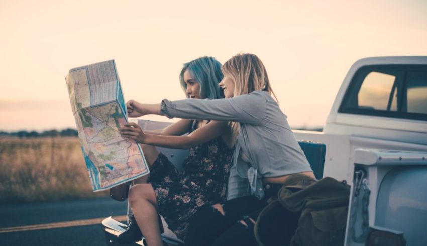 Two young women looking at a map in the back of a truck.