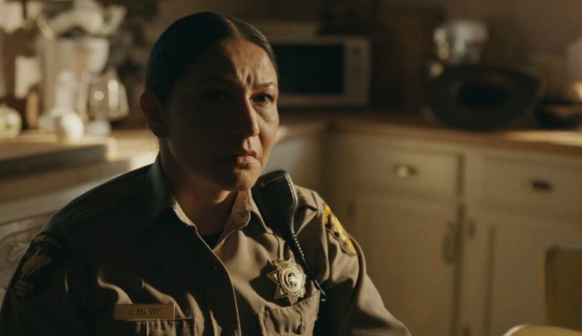 A woman in a police uniform sitting in a kitchen.