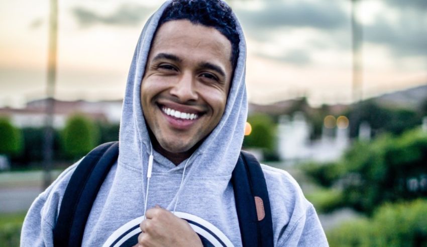 A young man in a gray hoodie smiling.