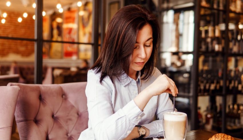 A woman is sitting at a table with a cup of coffee.