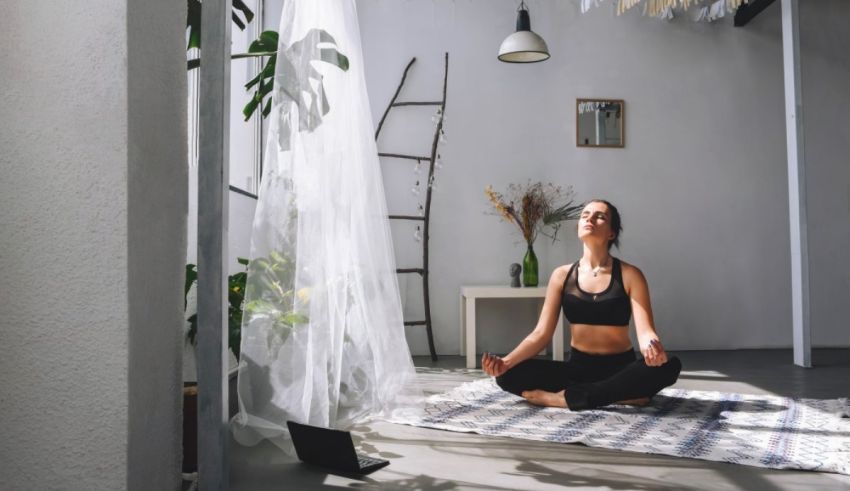 A woman is meditating in a room with plants.