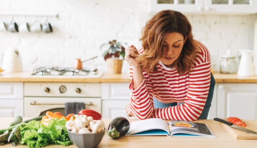 A woman reading a cookbook in the kitchen.