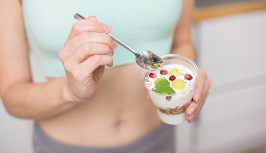 A woman is holding a cup of yogurt with berries in it.