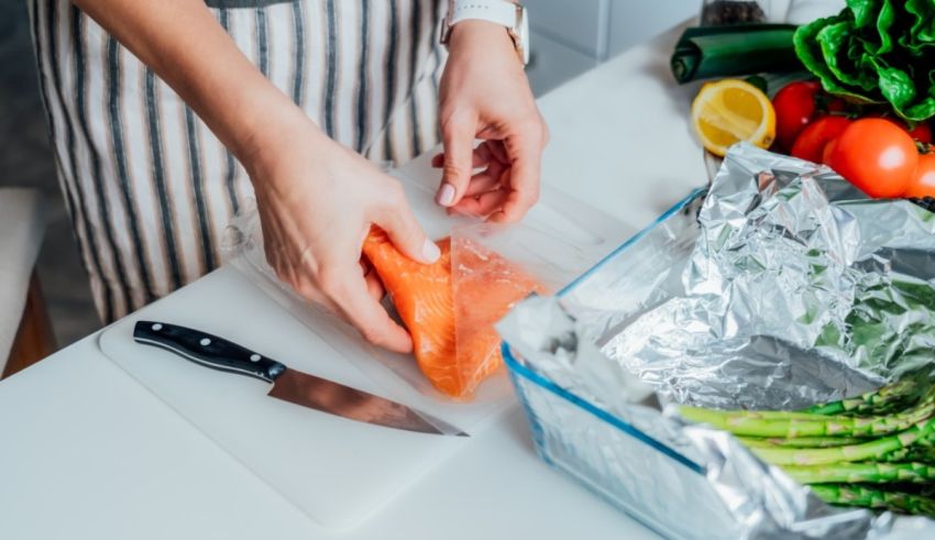 A woman is preparing salmon in a plastic bag.