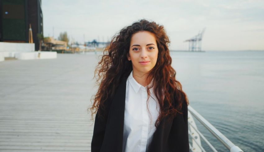 A young woman with curly hair standing on a dock.