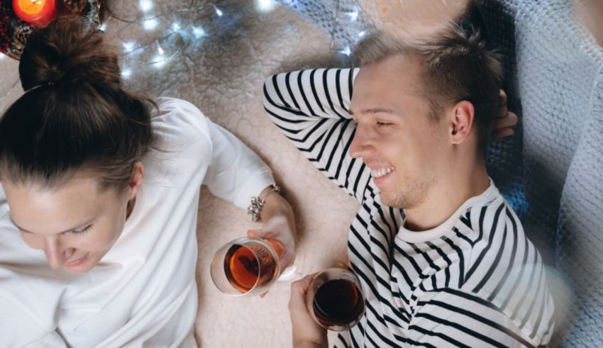 A man and woman are laying on the floor with a glass of wine.