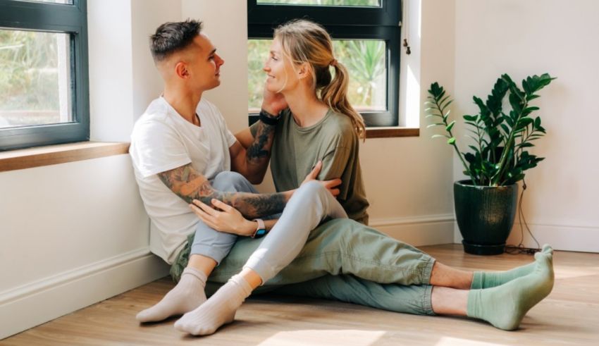 A couple sitting on the floor in front of a window.