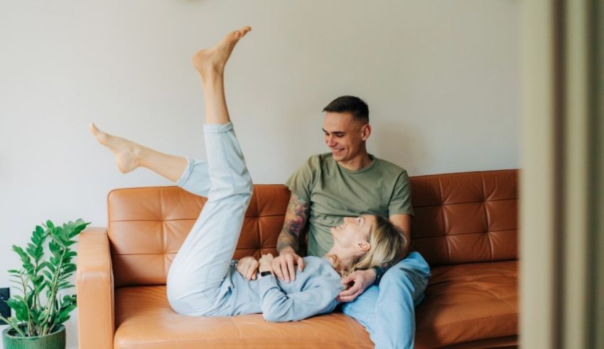 A man and woman are sitting on a couch in their home.