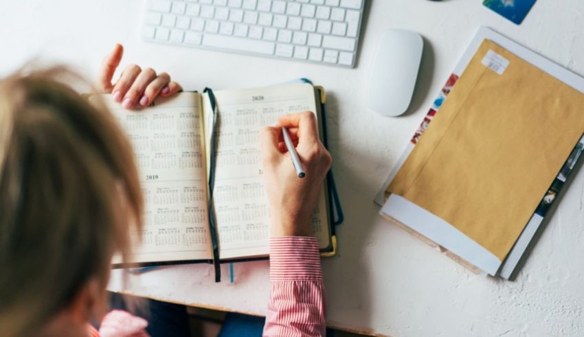 A woman is writing in a notebook at her desk.