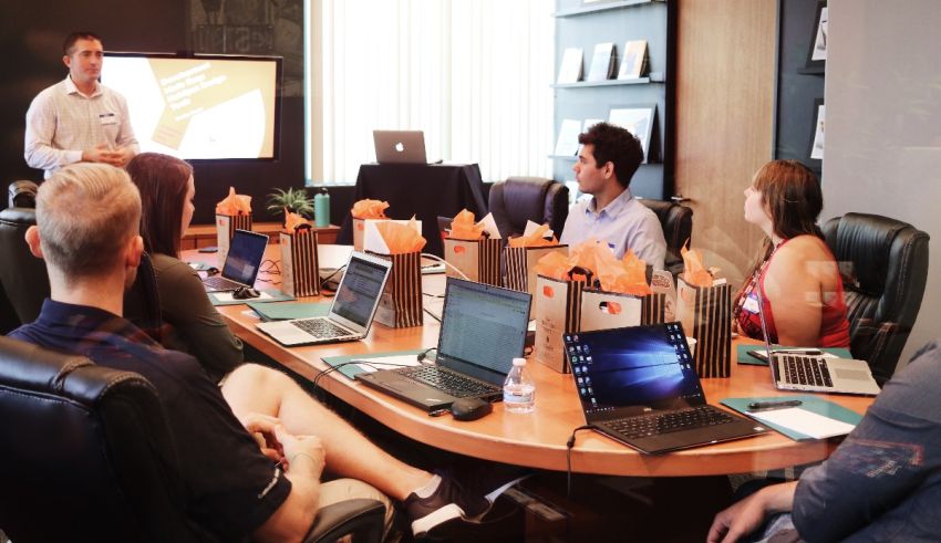 A group of people sitting around a table with laptops.