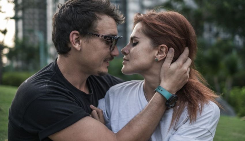 A man and woman hugging in a park.