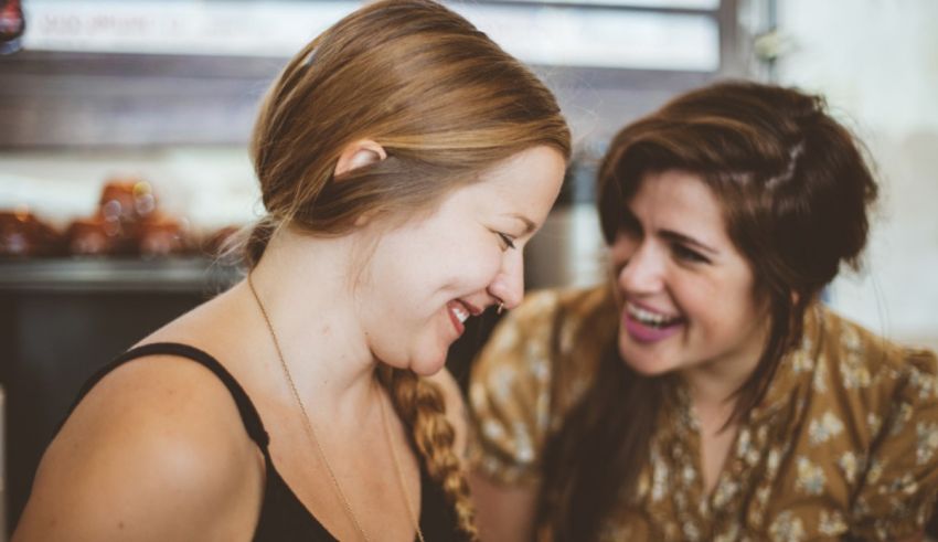 Two women laughing at each other in a coffee shop.