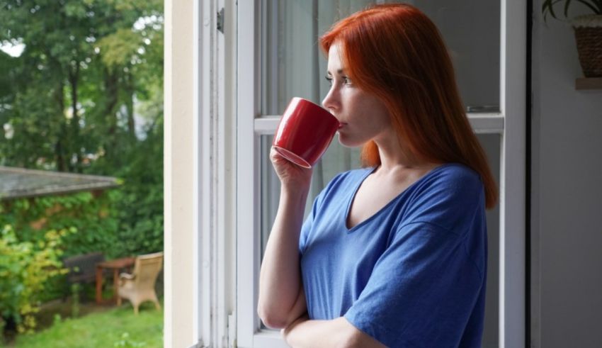 A woman drinking coffee out of a window.