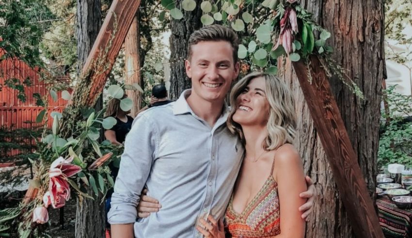 A man and woman posing for a photo in front of a tree.