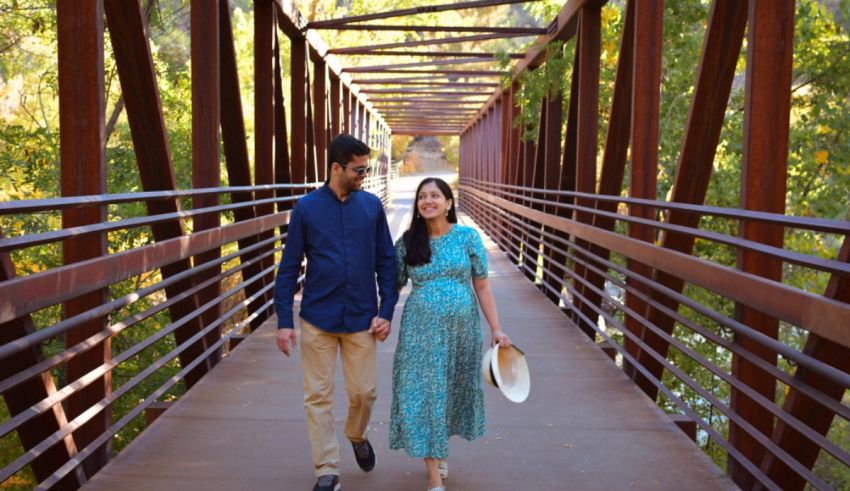 A couple walking on a bridge in the woods.