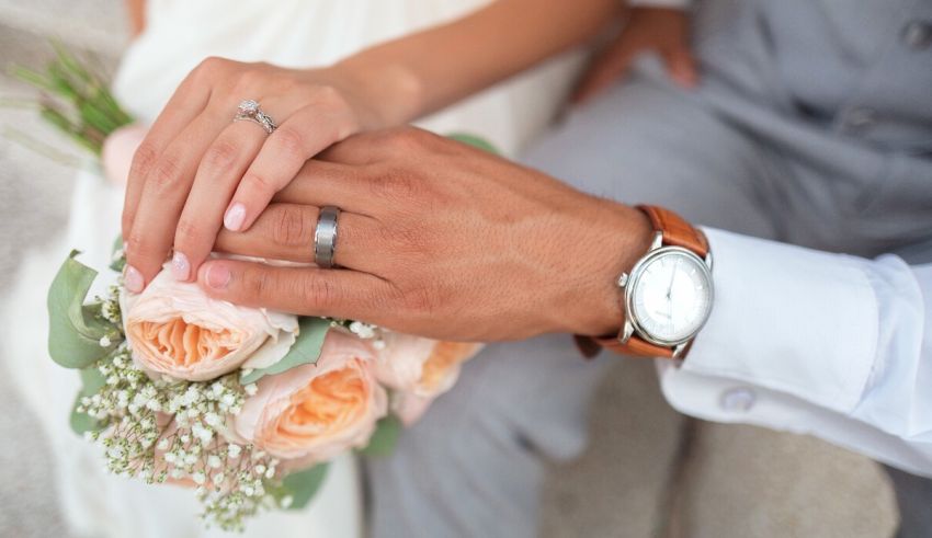 A bride and groom holding hands while holding a bouquet of roses.