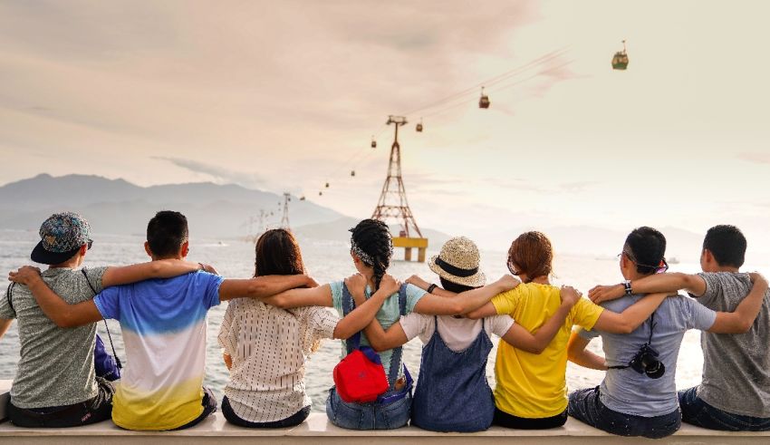 A group of people sitting on a ledge looking at the ocean.