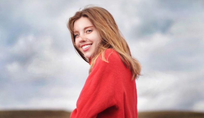 A woman in a red sweater standing in a field.