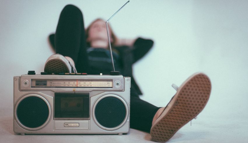 A person laying on the floor next to a boombox.