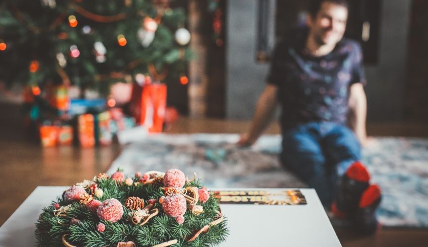 A man sitting on the floor next to a christmas tree.