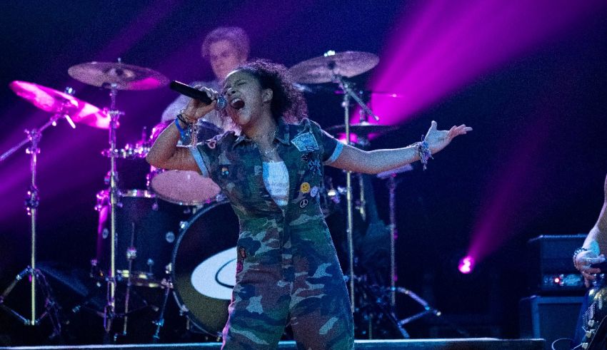 Two women in camouflage outfits singing on stage.