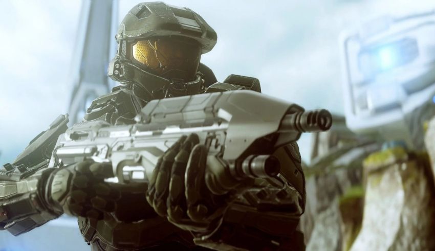 Halo master chief is holding a gun in front of a mountain.