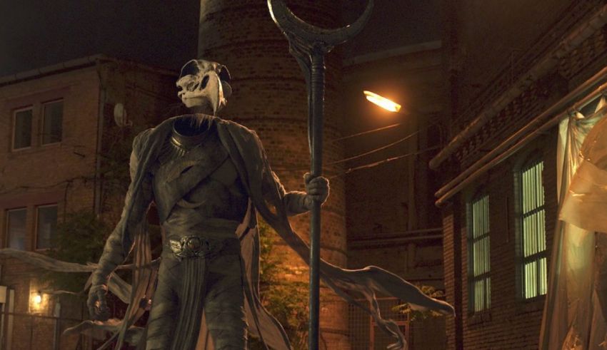 A statue of a skeleton standing on a street at night.