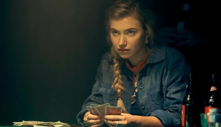 A young woman playing cards in a dark room.