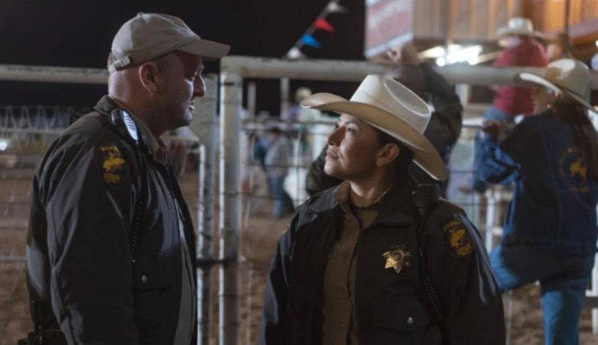 Two cowboys standing next to each other at a rodeo.