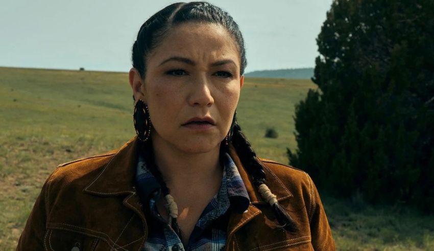 A woman in a brown jacket standing in a field.