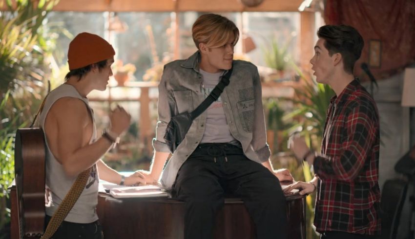 Three men are sitting on a table talking to each other.