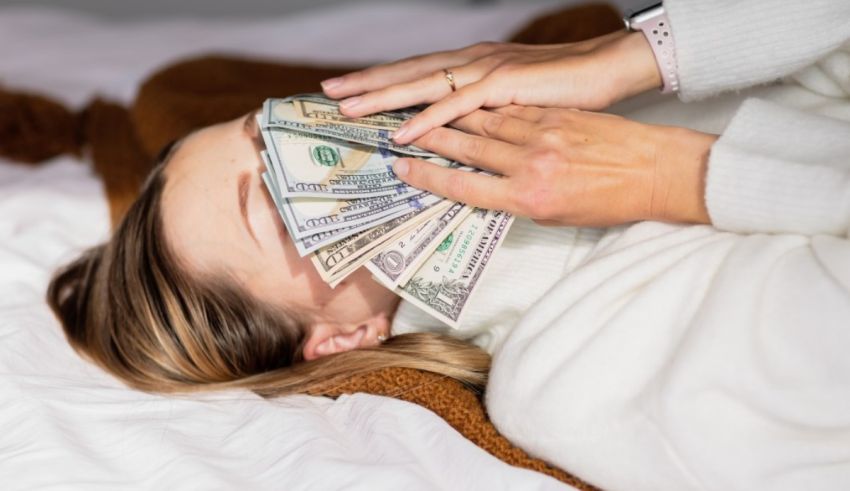 A woman laying on a bed with money on her face.