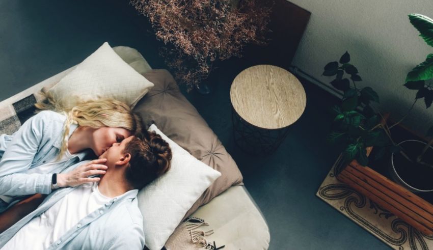 A man and woman are laying on a bed and kissing.