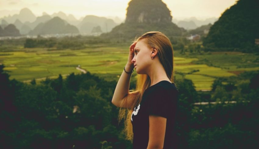 A girl with long hair standing in front of a mountain.