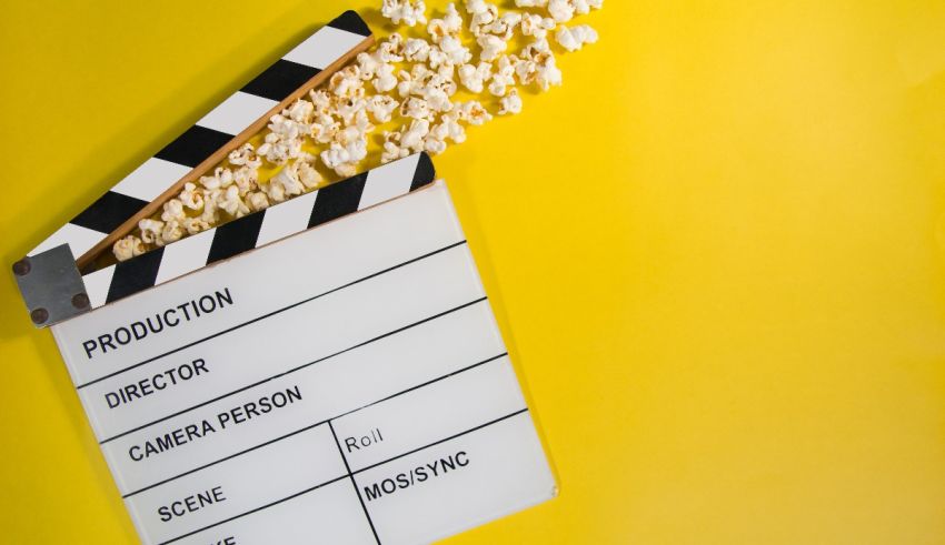 A clapper board with popcorn on a yellow background.
