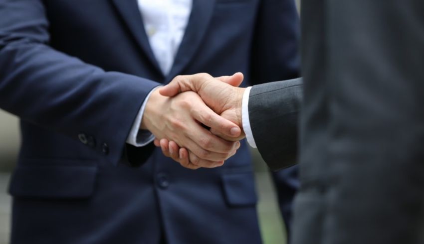 Two businessmen shaking hands in front of a building.