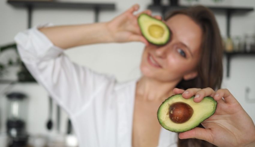 A woman holding an avocado in front of her eyes.