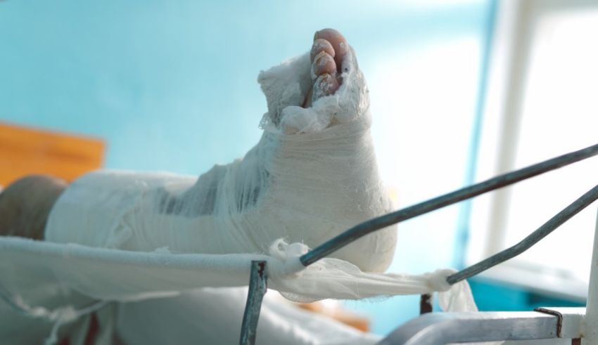 A person's foot is wrapped in a bandage in a hospital bed.