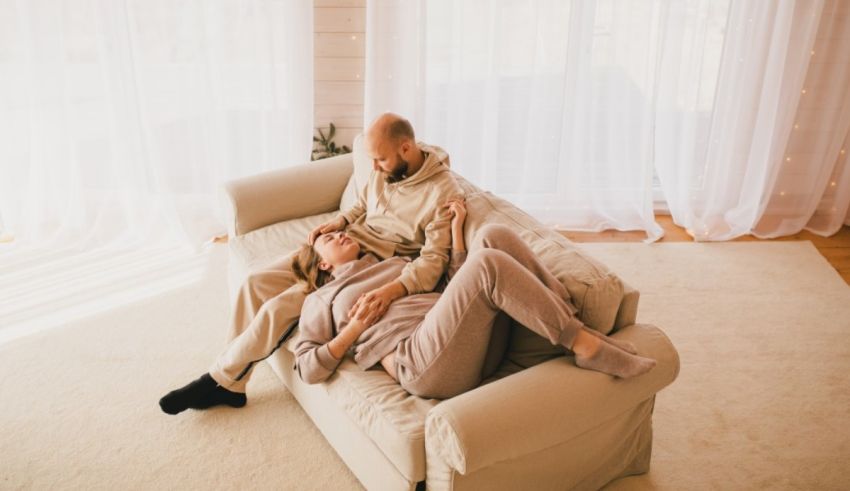 A man and woman are sitting on a couch in their home.