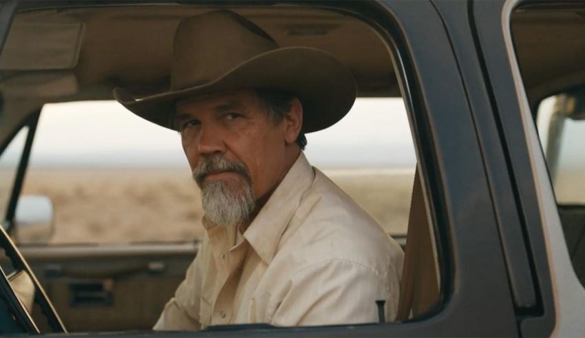 A man in a cowboy hat sits in the driver's seat of a car.