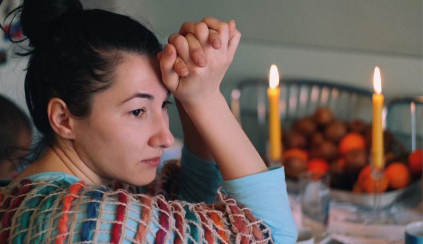 A woman sits at a table with candles in front of her.